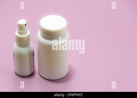 Medical plastic spray bottles and pills on pink background. Medicine packs. Industrial bottles. Generic drugs. Stock Photo
