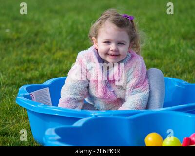 Toddler sat in sand pit playing, UK Stock Photo