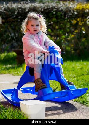 Toddler on a rocking horse in the garden, UK Stock Photo