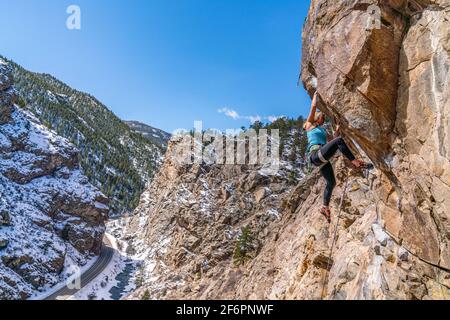 Woman rock climber navigates her up a rock face in Golden, CO Stock Photo