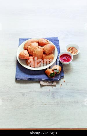 Italian panzerotti with spinach hazelnuts and tomato sauce Stock Photo