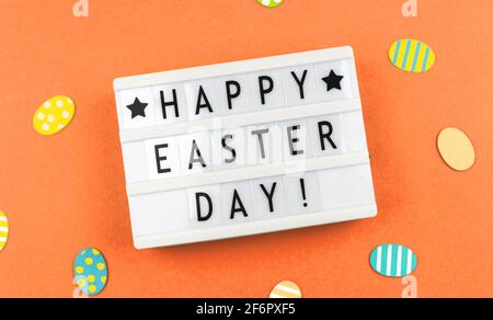 Happy Easter Day text background with greetitngs and easter eggs, orange paper and flat lay photo Stock Photo