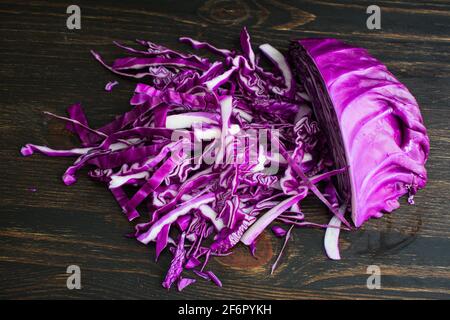 Shredded Red Cabbage on a Dark Wood Background: Sliced purple cabbage on a wooden cutting board Stock Photo