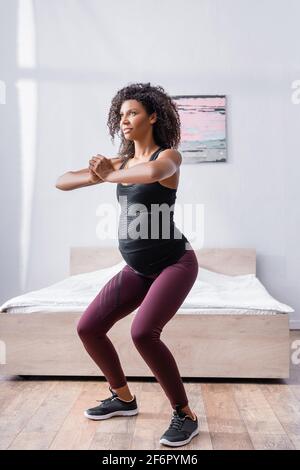 Pregnant african american woman working out in bedroom Stock Photo