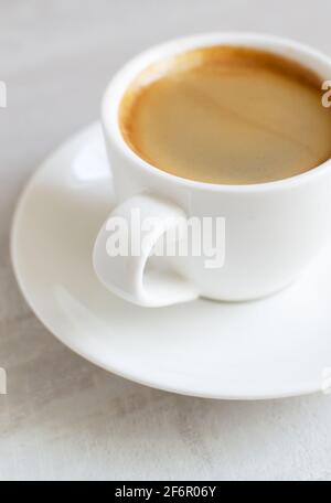 Fragrant espresso in a white cup and saucer. Morning of tradition. Homemade coffee making concept. Vertical orientation. Close-up. Stock Photo