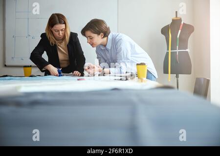 Fashion expert teaching trainee on proper cutting of fabric Stock Photo