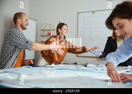 Two colleagues reaching for smartphone in tailoring teacher hand Stock Photo