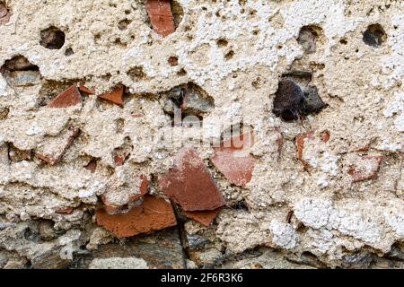 Old damaged dirty wall with cracks and wholes. Ruin facade made of natural stone and Bricks. A vintage background for design Stock Photo