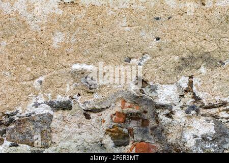 Old damaged dirty wall with cracks and wholes. Ruin facade made of natural stone and Bricks. A vintage background for design Stock Photo