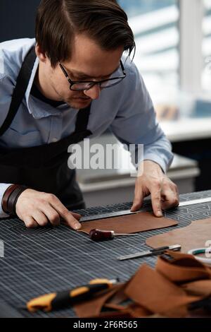 Skilled leather manufacture worker cutting some samples. Stock Photo