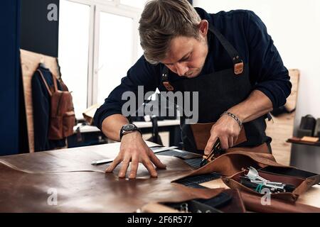Skilled leather manufacture worker cutting some samples. Stock Photo