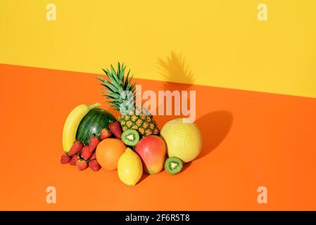 Pile of exotic fruits isolated on a colored background. Heap of fresh organic fruits minimalist on an orange table in bright light. Stock Photo
