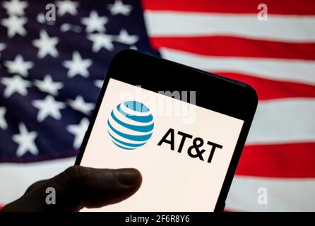 In this photo illustration the world's largest telecommunications company, the second largest provider of mobile telephone services AT&T logo is seen on an Android mobile device with United States of America (USA), commonly known as the United States (U.S. or US), flag in the background. Stock Photo