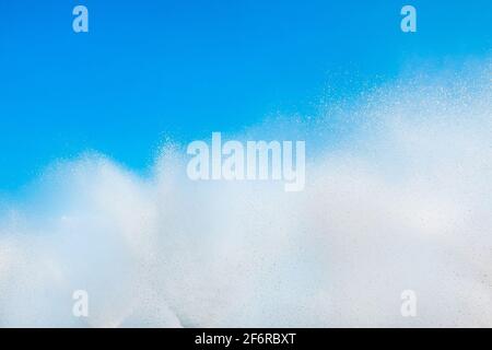 A fountain splashes and drops against a beautiful, bright, blue sky background. Stock Photo