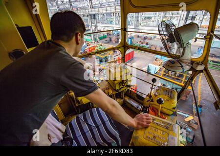 Bearing production plant. Overhead crane operator in cabin. Factory workshop on background. Man is out-of focus. Stepnogorsk, Kazakhstan Stock Photo