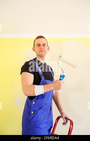 A man paints the wall in the house with a roller and paint. Renovation of rooms in the house. Stock Photo