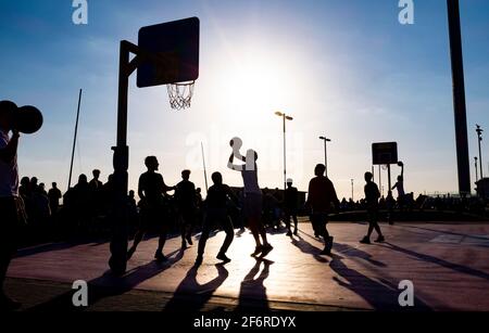 Brighton UK 2nd April 2021 - Basketball players on Brighton seafront enjoy the late afternoon sunshine on Good Friday but the forecast is for much colder weather by Monday with snow predicted for some areas of the UK :  Credit Simon Dack / Alamy Live News Stock Photo