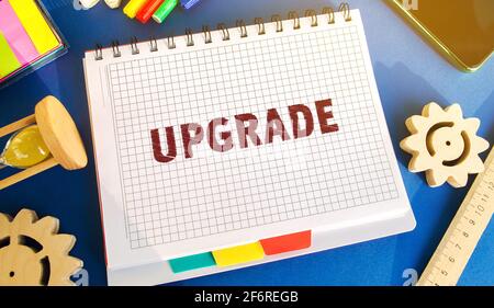 Notebook with inscription Upgrade. Improvement, modernization and renewal concept. Upgrading software or hardware to a more recent version. Gears, hou Stock Photo
