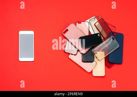 Choice of multicolored plastic back covers for mobile phones on red background with a smart phone on the side Stock Photo
