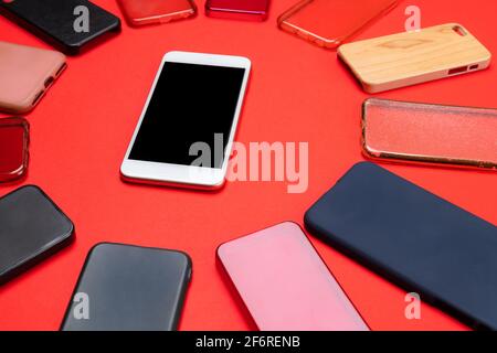 Choice of multicolored plastic back covers for mobile phones on red background with a smart phone on the side Stock Photo