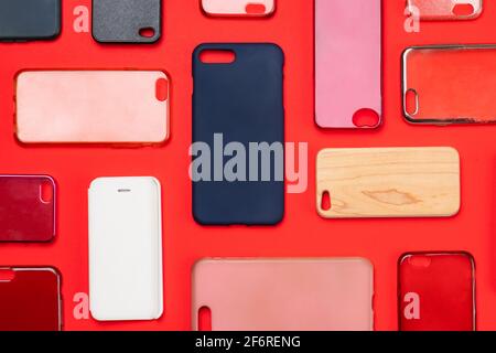 Pile of multicolored plastic back covers for mobile phone. Choice of smart phone protector accessories on red background. A lot of silicone phone back Stock Photo