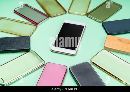 Choice of multicolored plastic back covers for mobile phones on green background with a smart phone on the side Stock Photo
