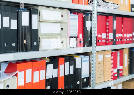 Colourful blank blind folders with files in the shelf. Archival, stacks of documents at the office or library. Physical document storage units Stock Photo