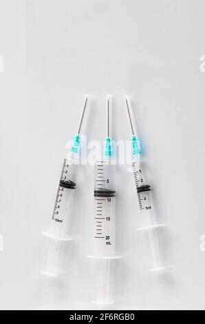 Three syringes with vaccine, of different capacities, on the table in the hospital, prepared for injections. Copy space, vertical image. Stock Photo
