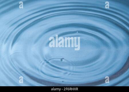 Circles on the blue water from falling raindrops. Close-up. Background image Stock Photo