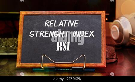 Relative Strength Index RSI words in white color on a black styling board in a wooden frame in the workplace next to the monitor and computer mouse. F Stock Photo