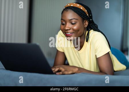partial view of curly girl using laptop with blank screen in bed during ...
