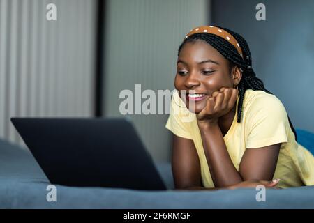partial view of curly girl using laptop with blank screen in bed during ...