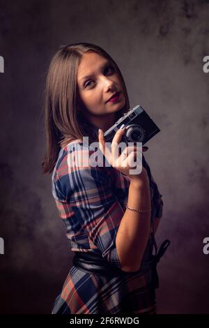 Girl photographer with retro camera, studio photography on gray background.