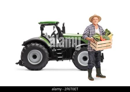 Mature farmer with a tractor carrying a crate full of organic ...