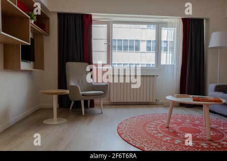 modern living room with a grey chair, small round table, bookshelves and TV Stock Photo