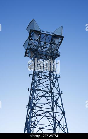looking up at a microwave relay tower with blue sky background Stock Photo