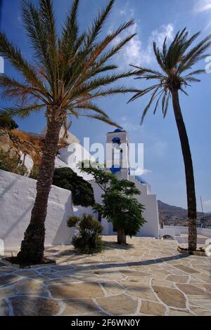 Beautiful whitewashed church next to palm trees in Ios cyclades Greece Stock Photo