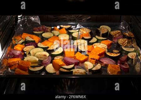 Roasted vegetables on sheet pan in the oven. Concept of healthy eating. Stock Photo