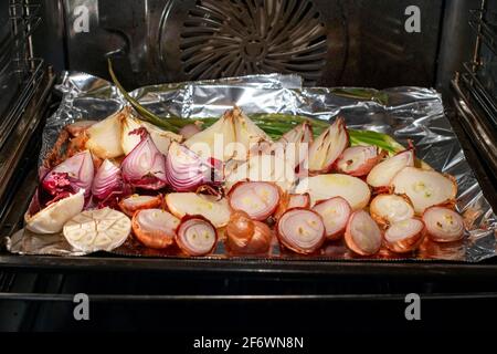 Roasted onions and garlic in the oven. Concept of healthy eating. Stock Photo