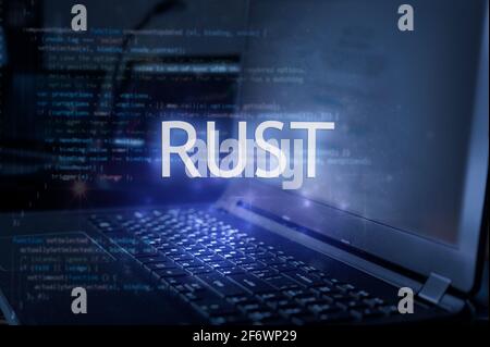 Rust inscription against laptop and code background. Technology concept. Learn programming language. Stock Photo