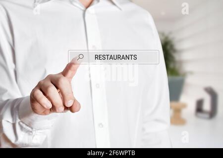 Man press the search icon on a virtual screen bar with the word restaurants. Online search for a restaurant on the internet Stock Photo