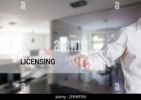 Male hand pressing the word licensing on a virtual search display bar. Concept of patenting or copyright protection Stock Photo