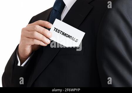 Businessman takes out a business card with the word testimonials written on it. Business personal recommendation concept. Stock Photo