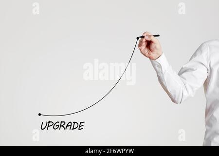 Businessman hand draws a rising line with the word upgrade. Improvement, modernization and renewal in business or technology concept. Stock Photo
