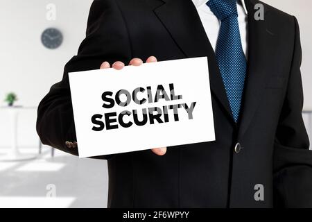 Businessman holds a card with the word social security written. Stock Photo