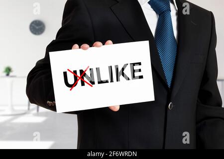 Businessman holds a card with the word unlike transformed into like. Stock Photo