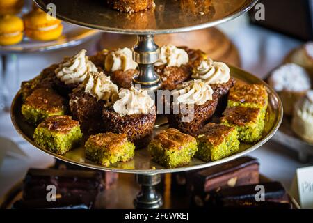 Pistachio cake and orange-almond cake sit within easy reach on a tiered étagère at afternoon tea in Hotel Endsleigh, West Devon, England. Chef José Graziosi, who has run Endsleigh's kitchen since 2015, prepares the sweets served at the hotel's daily Devonshire Cream Tea. Stock Photo