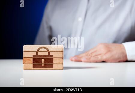 Padlock icon carved on wooden blocks with a businessman on the background. Technological security or safety concept. Stock Photo
