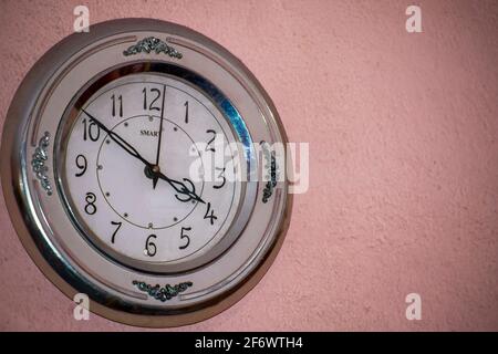 decorative metal wall clock hanging on a stucco wall isolated