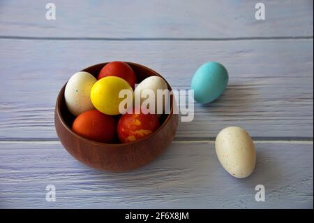 Colorful Easter eggs in wooden bowl on wooden background Stock Photo
